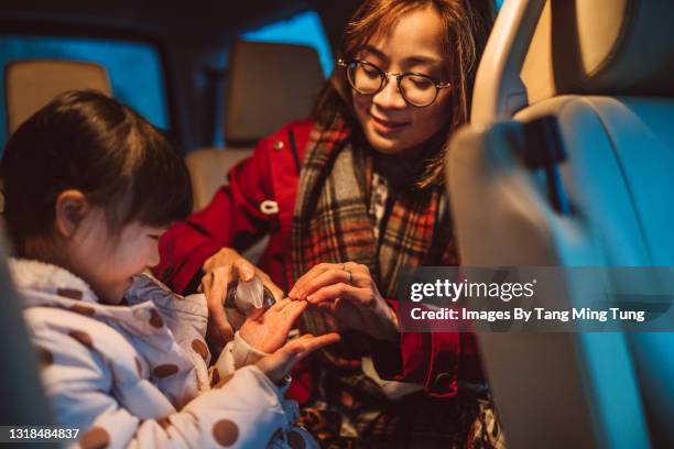 mom squeezing hand sanitizer onto her littler daughter’s hands in car - hand sanitizer in car stock pictures, royalty-free photos & images