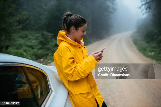 auf der suche nach wegbeschreibungen online - frau mit gelben regenmantel stock-fotos und bilder