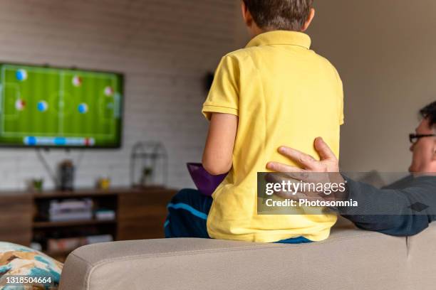 rückansicht von opa und enkel, der sich auf der couch im wohnzimmer entspannt vor dem fernseher sieht - soccer back stock-fotos und bilder