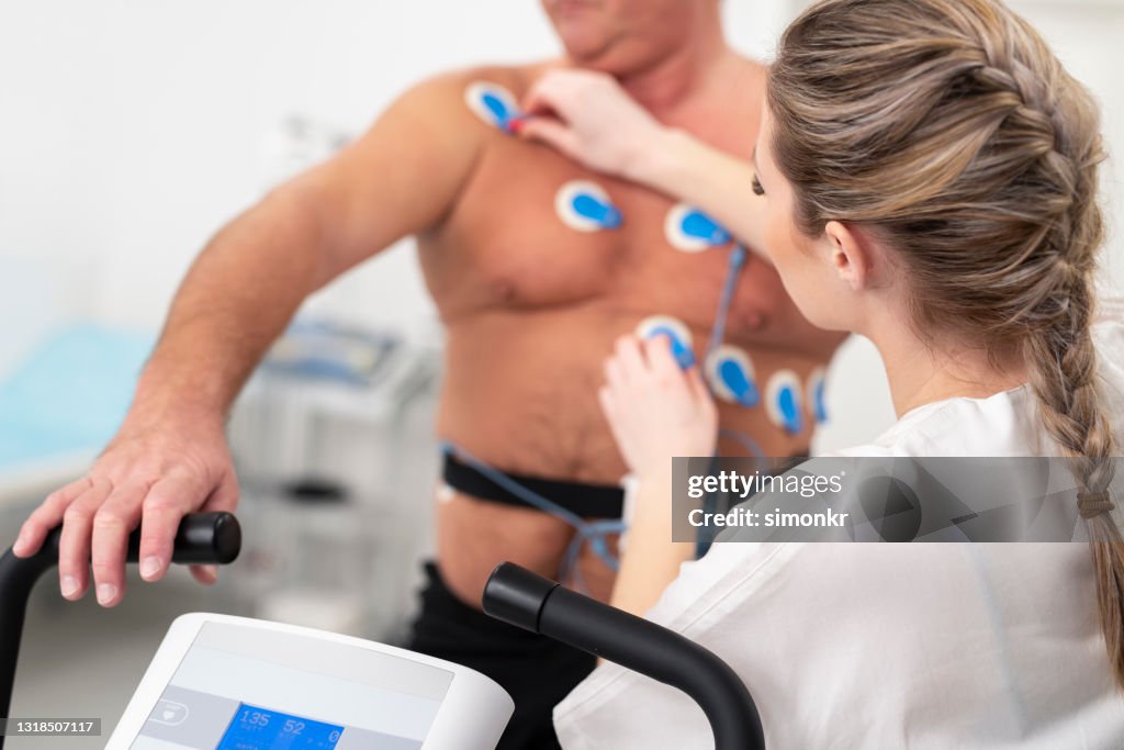 Female doctor placing electrodes on the chest of a mature man