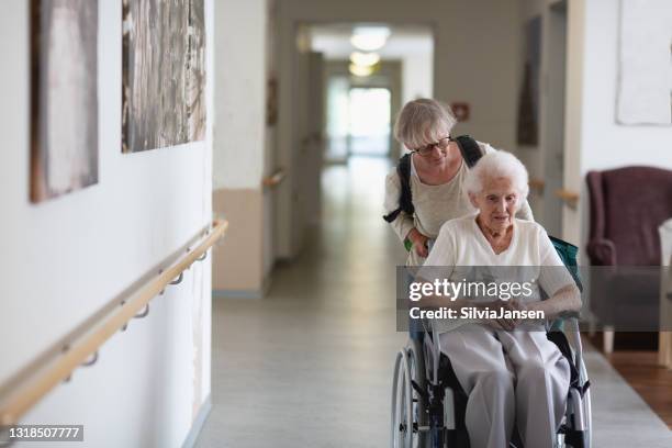 caregiver helping senior woman in wheelchair - retirement home stock pictures, royalty-free photos & images