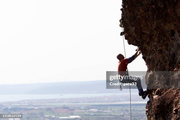 athletic man climbing on overhanging cliff rock - yolo county stock pictures, royalty-free photos & images