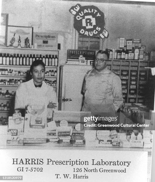 Interior view of The Harris Prescription Laboratory as two sales clerks stand behind a pharmacy counter, Tulsa, Oklahoma, 1940s or 1950s.