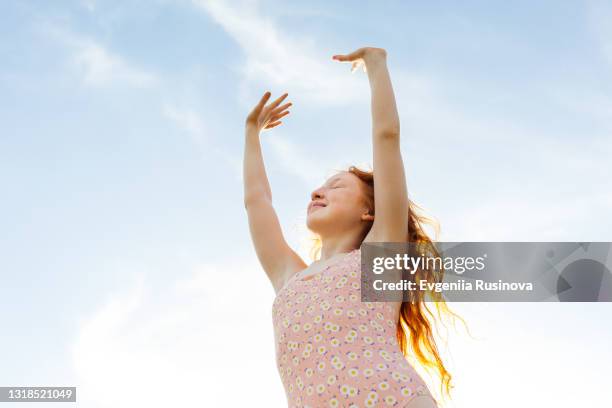 red-haired girl stretches her hands to the sky - early childhood stock pictures, royalty-free photos & images