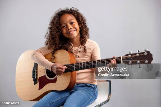 young girl playing the guitar and looking at camera - plucking an instrument stock pictures, royalty-free photos & images