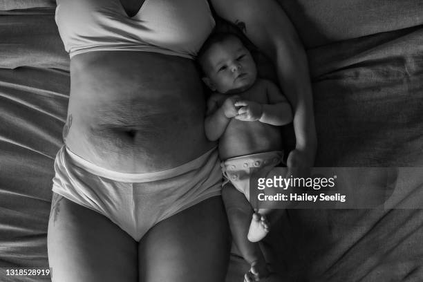 un bambino giace accanto allo stomaco delle sue madri - addome umano foto e immagini stock
