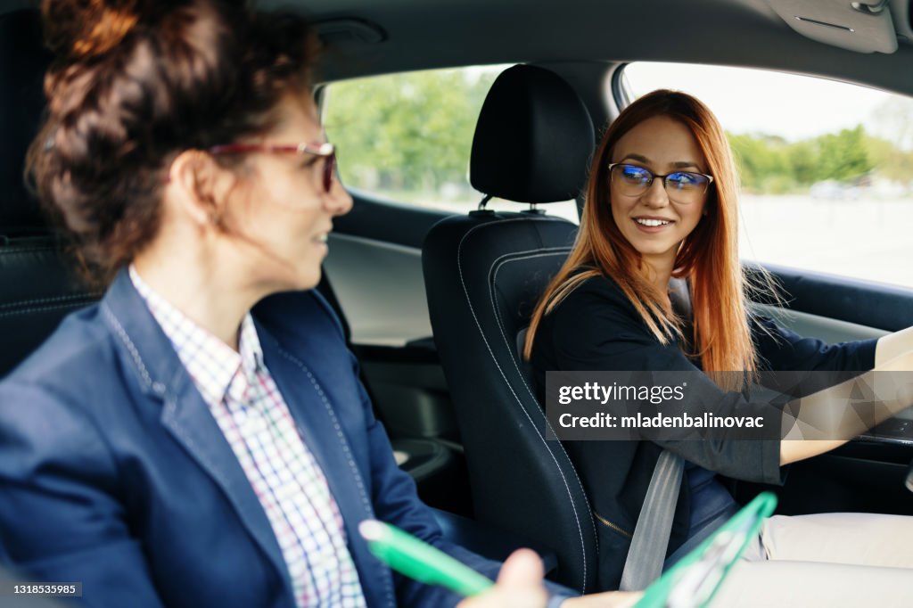 Driving school or test. Beautiful young woman learning how to drive car together with her instructor.
