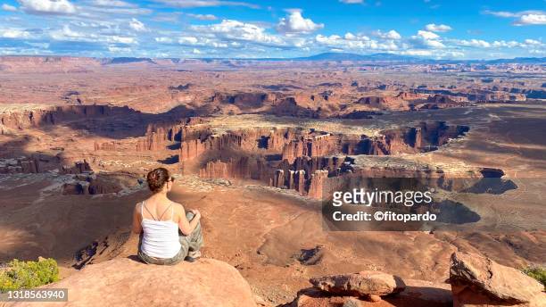 a woman sits on the edge of a canyon in canyonlands national park - island in the sky stock pictures, royalty-free photos & images