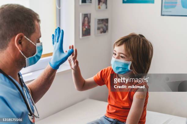 doctor and cute boy giving each other high-five after covid-19 vaccination. child vaccination. coronavirus epidemic. copy space. - child mask stock pictures, royalty-free photos & images