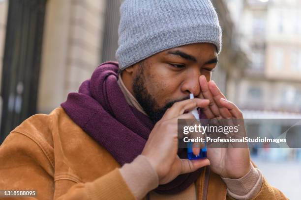 jovem afro-americano com máscara facial protetora está tendo problemas de sinusite fora da natureza. - nose mask - fotografias e filmes do acervo