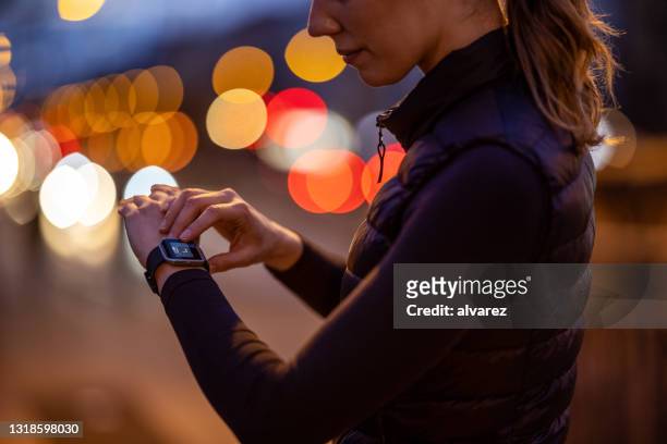 woman using fitness app on her smartwatch - competition time stock pictures, royalty-free photos & images