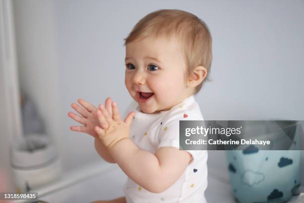 a 1 year old baby girl clapping her hands on her baby-changing table - babies bildbanksfoton och bilder