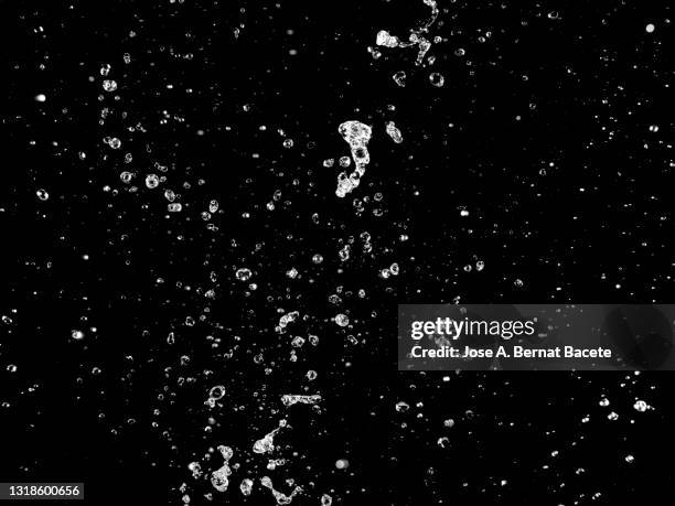 explosion with water drops and splashes on a black background. - gota de lluvia fotografías e imágenes de stock