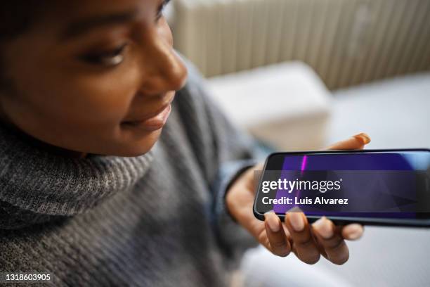 african female using voice assistant on smartphone - rede stock-fotos und bilder