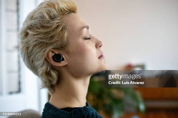 woman relaxing by listening to mindful music - in ear headphones photos et images de collection