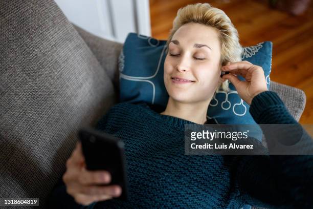 woman listening to mindful music on smart phone - krankheitsverhinderung stock-fotos und bilder