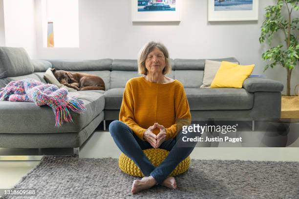 senior woman meditating at home - zen dog stock pictures, royalty-free photos & images