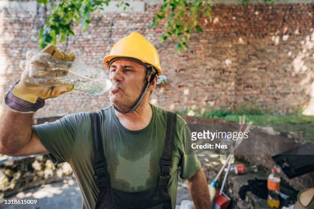 el trabajador bebe agua - calor fotografías e imágenes de stock