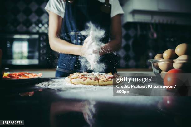 midsection of man preparing pizza at home - dunkler hintergrund frau quer stock-fotos und bilder