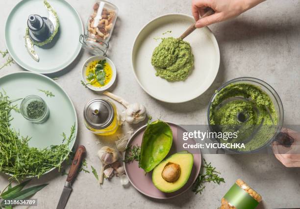 homemade guacamole with chickpeas on grey concrete background with woman hands - guacamole stock-fotos und bilder