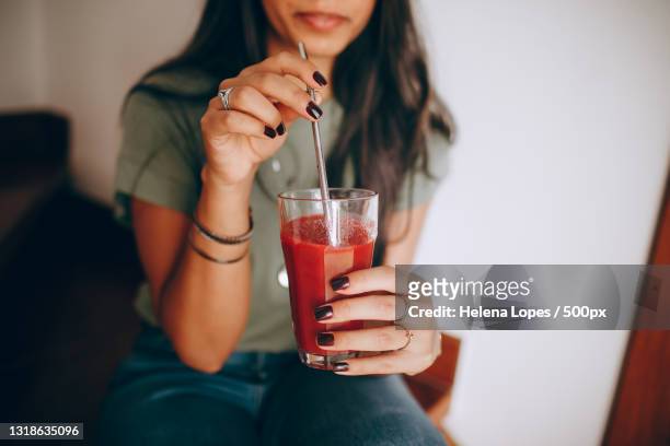 midsection of woman holding drink in glass - rietje stockfoto's en -beelden