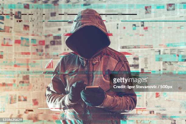 hooded hacker person using smartphone in infodemic concept - misinformation ストックフォトと画像