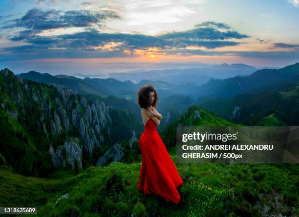 young woman in red dress standing on mountain against sky during sunset,romania - red dress photos et images de collection