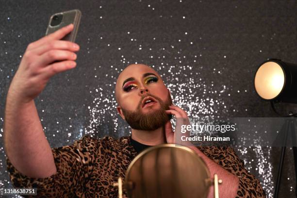 foto de um jovem usando um smartphone para tirar selfies depois de aplicar maquiagem teatral em um estúdio - beautiful transvestite - fotografias e filmes do acervo