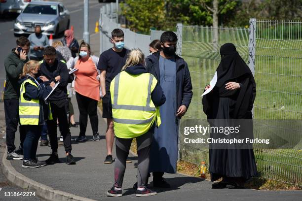 People queue for Covid-19 vaccinations at the ESSA academy in Bolton where mass vaccinations are taking place to try and combat rising levels of the...