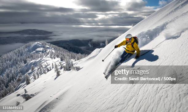 man skiing on snowcapped mountain against sky,pokljuka,slovenia - professional skier stock pictures, royalty-free photos & images