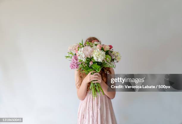 girl holding flowers against wall,auckland,new zealand - new zealand foto e immagini stock