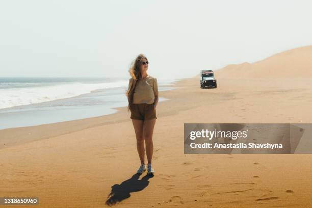 young woman exploring the wild dune coast of sandwich harbour by car in namibia - walvis bay stock pictures, royalty-free photos & images