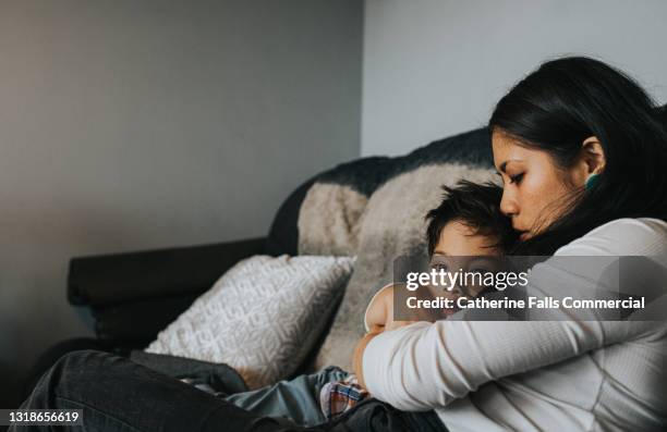 a mother holds her sky little boy close to her chest, and he tenderly rests his head on her - child nervous ストックフォトと画像