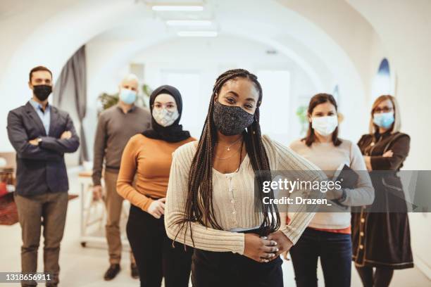 group of business people standing in office after reopening, wearing face masks and looking into camera - reopening ceremony stock pictures, royalty-free photos & images