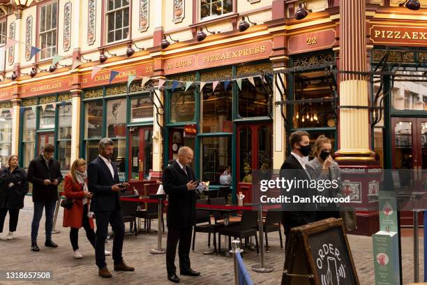 Workers queue for a restaurant in Leadenhall Market in the square mile on May 18, 2021 in London, England. Workers have begun to return to the City...