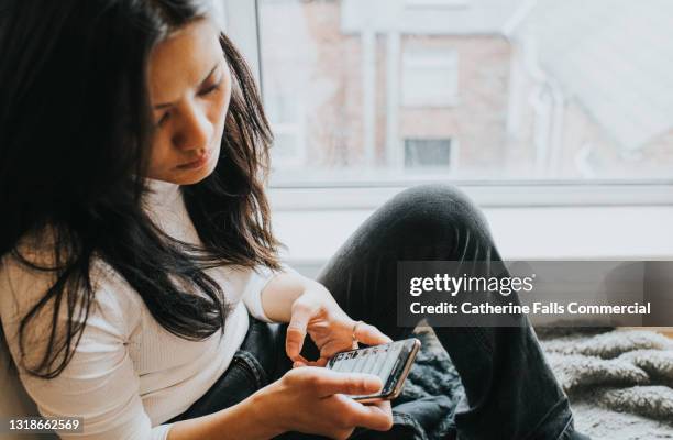 a perplexed woman checks her smart phone - sitting on floor stock pictures, royalty-free photos & images