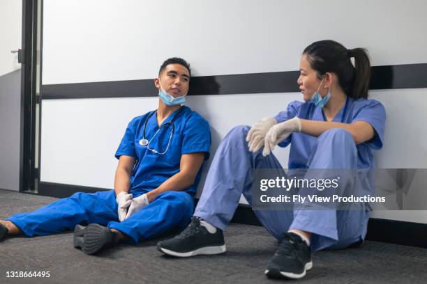 exhausted nurses take a break from their stressful shift - tired healthcare worker stock pictures, royalty-free photos & images