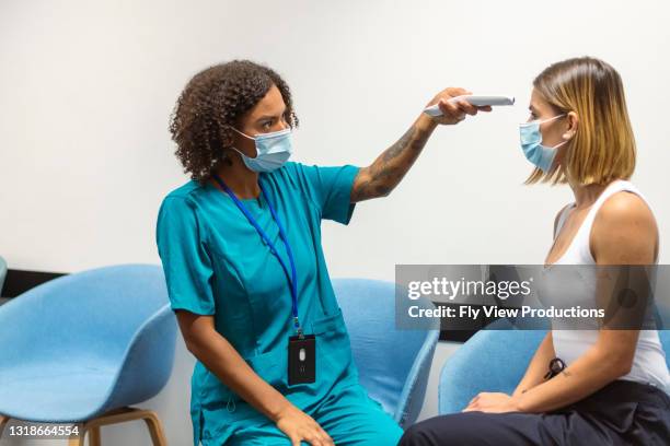 female healthcare worker checks sicks patient temperature - medical tourism stock pictures, royalty-free photos & images