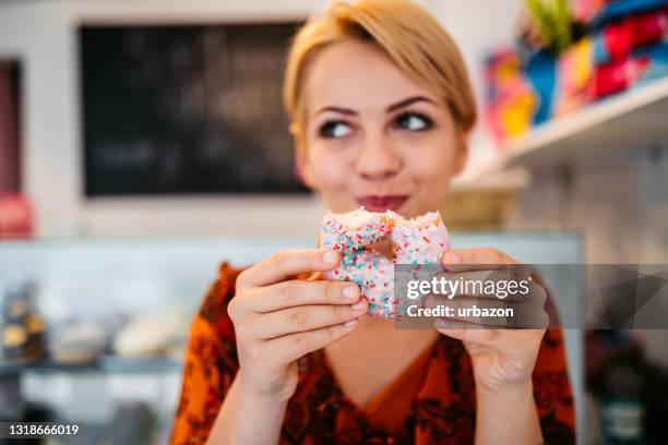 frau isst donut in der bäckerei - chocolate closed eyes stock-fotos und bilder