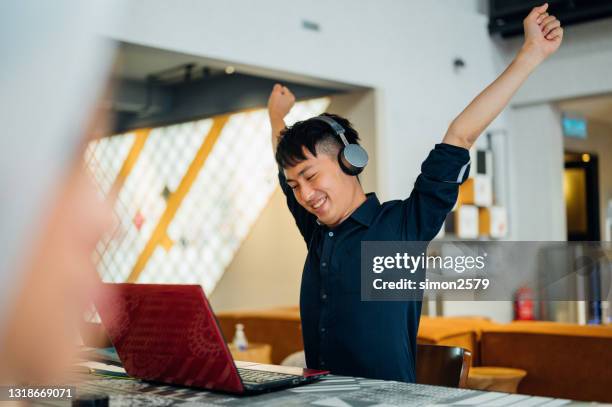 lächelnder geschäftsmann streckt rücken und arme am schreibtisch am arbeitsplatz im modernen büro - overtime sport stock-fotos und bilder