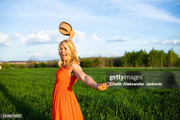 una joven juguetona posando para una foto en un campo de suero de leche - orange dress fotografías e imágenes de stock