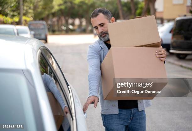 man loading donation boxes in his car - ramadan giving stockfoto's en -beelden