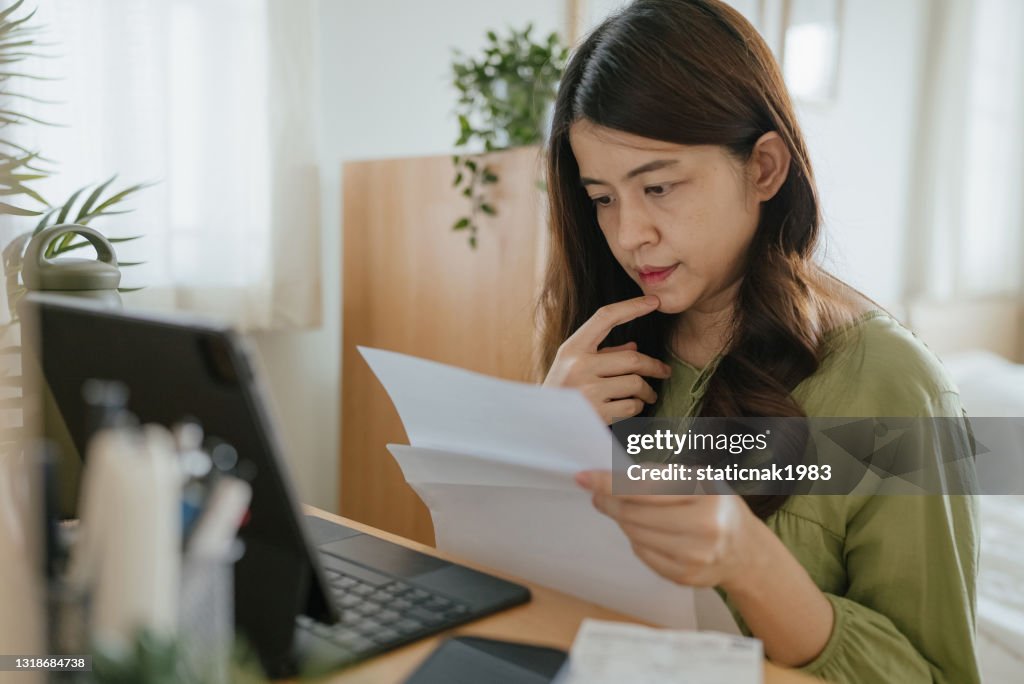 Mamma använder bärbar dator för att kontrollera ekonomin hemma.
