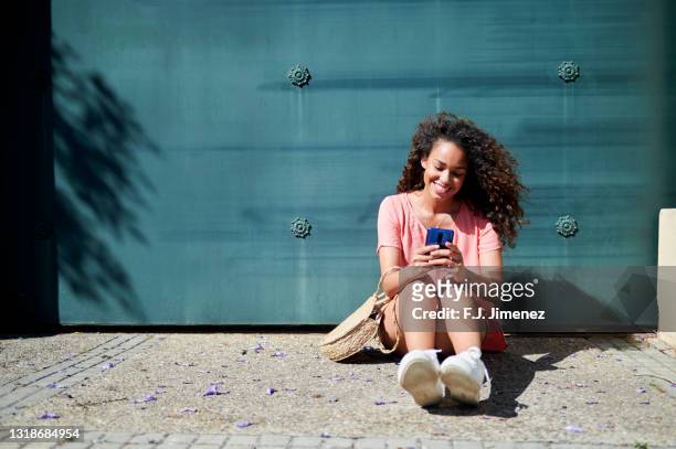 woman with afro hair using smart phone on the street - afro caribbean and american stock-fotos und bilder