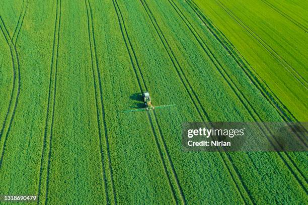 aerial view of agricultural tractor spraying wheat field - watering farm stock pictures, royalty-free photos & images