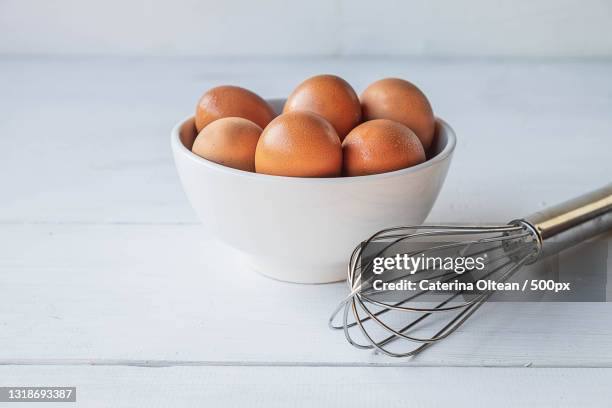 close-up of eggs in wire whisk on table - ballonklopper stockfoto's en -beelden
