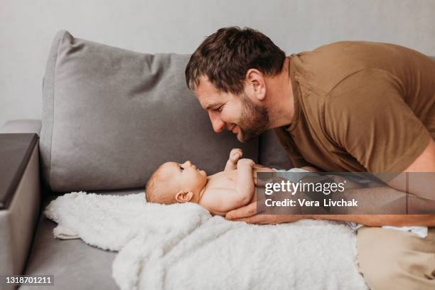 middle age caucasian father changing diaper for newborn baby daughter. male man parent taking care of child at home alone. authentic lifestyle candid moment. single dad family life concept. - changing nappy stock pictures, royalty-free photos & images