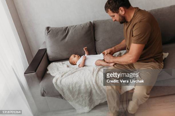 middle age caucasian father changing diaper for newborn baby daughter. male man parent taking care of child at home alone. authentic lifestyle candid moment. single dad family life concept. - adult baby boy diaper change foto e immagini stock