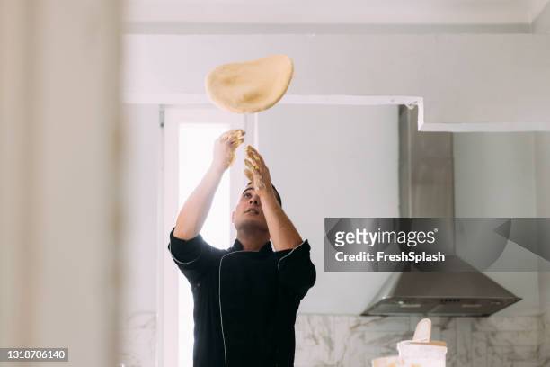 giovane chef professionista caucasico maschio che prepara pasti gustosi in una cucina privata - pizza toss foto e immagini stock