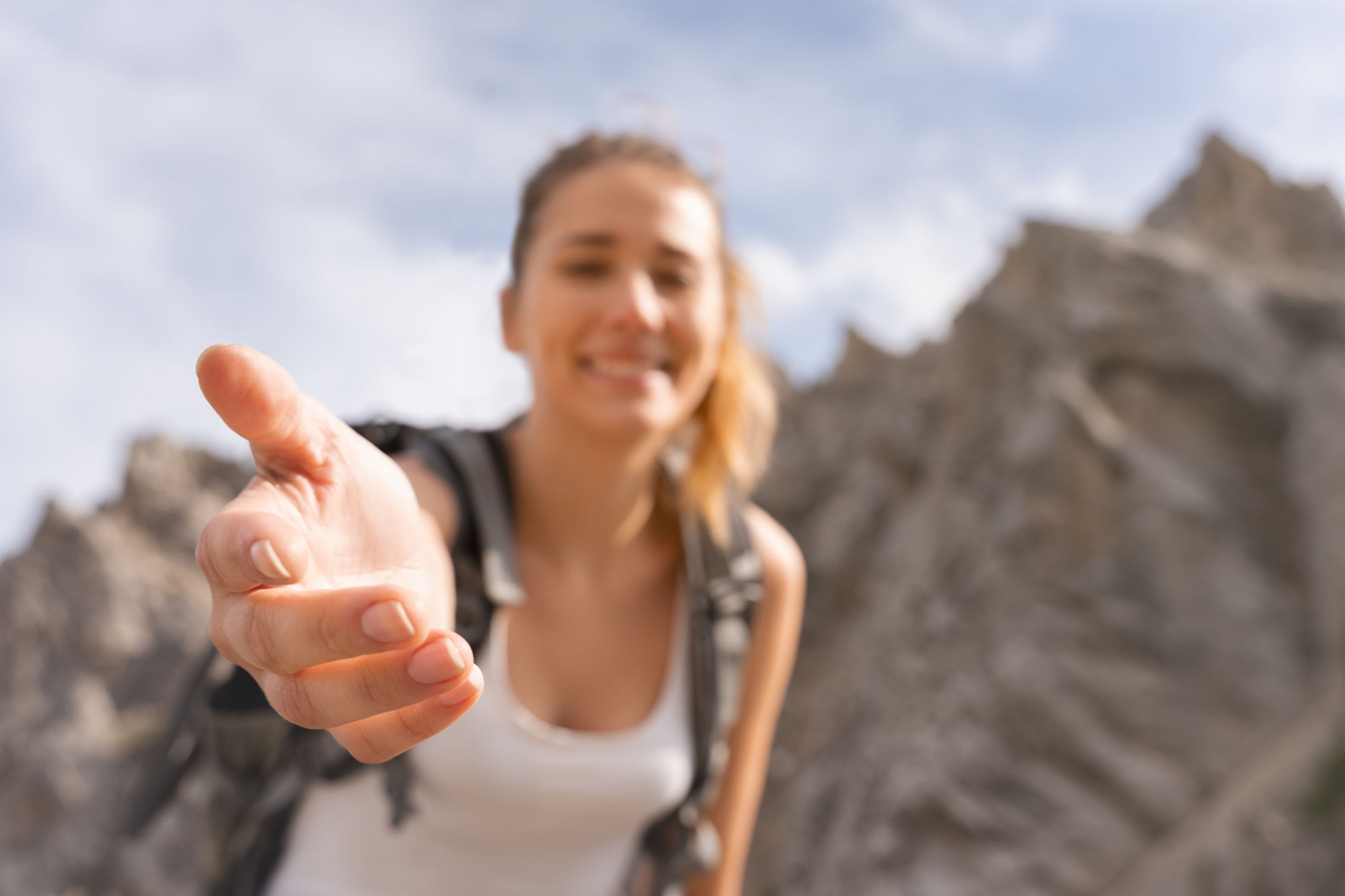 young man on top of the mountain, extending his hand to help you reach the summit young man on top of the mountain, extending his hand to help you reach the summit